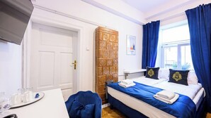 Una camera d'albergo con un letto, una scrivania, una sedia e una finestra con tende.