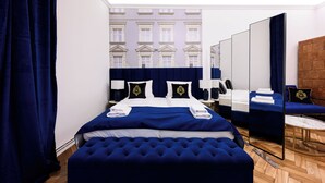 Una camera d'albergo con un letto grande, un'area salotto, uno specchio e vista su un edificio.