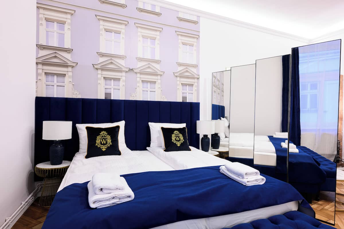 A hotel room with a large bed, two bedside tables, a mirror, and a view of a building through a window.