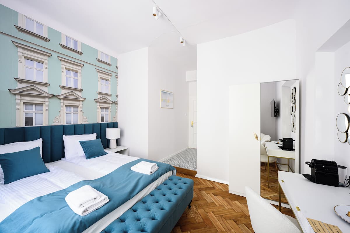 A modern hotel room with a large bed, a desk, and a mirror.