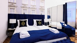 A hotel room with a large bed, two bedside tables, a mirror, and a view of a building through a window. - Wiślna Main Square Apartments Self Check-in (Kraków)
