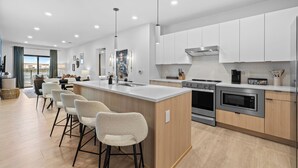 Una cocina moderna con una isla central, electrodomésticos de acero inoxidable y vistas al exterior.