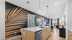Una cocina moderna con una isla central, un área de comedor con vistas y un espacio de estar con un gran ventanal.