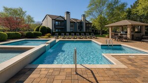 A swimming pool area with lounge chairs and a barbecue area.