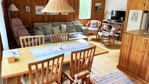 A cozy room with a wooden dining table, chairs, a sofa, and a television.