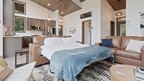 Un interior moderno con una cama, un sofá, una cocina y un comedor.