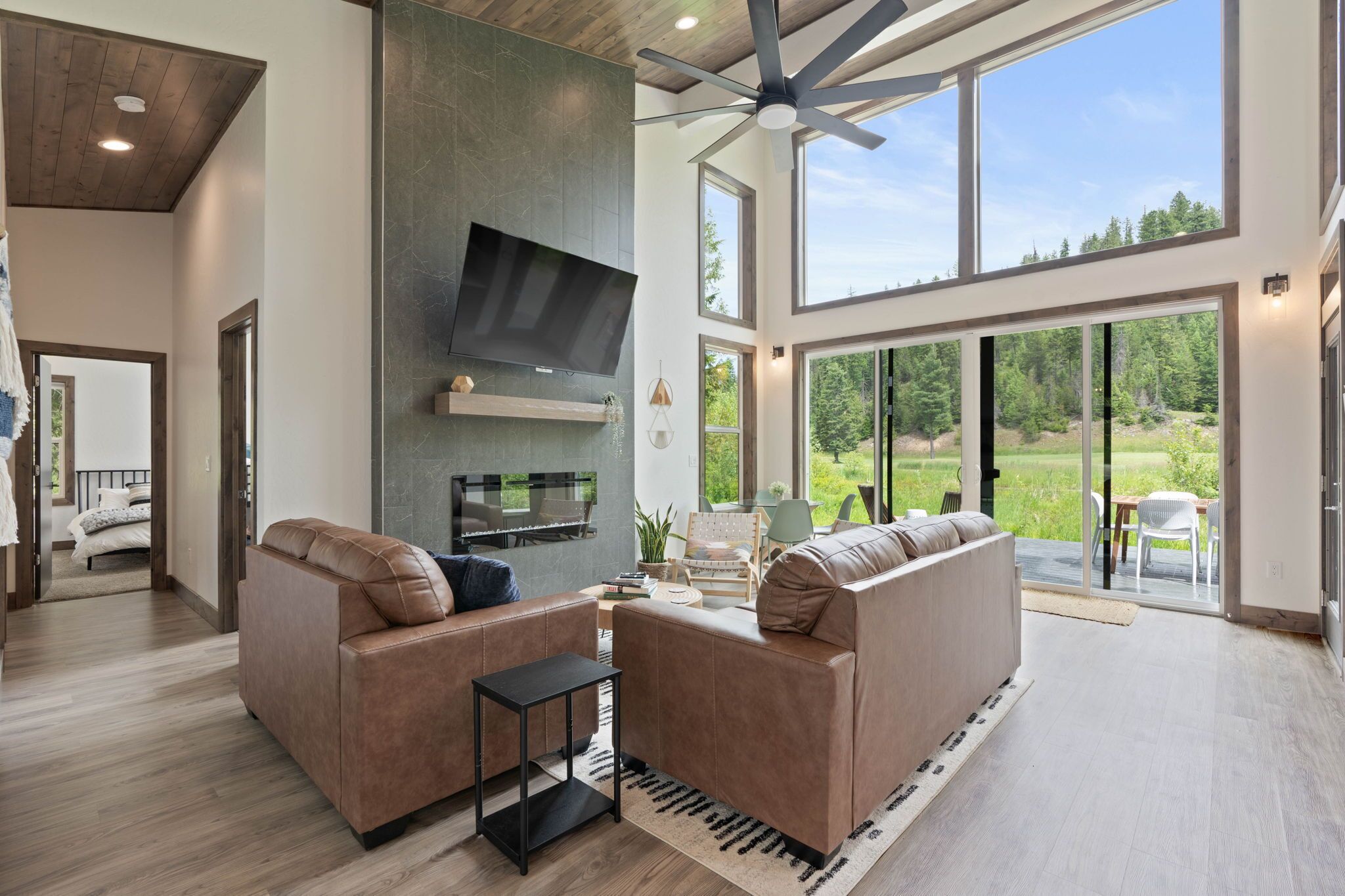 A spacious living room with a large TV, leather sofas, and a ceiling fan.