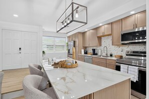 A modern kitchen with a marble island, stainless steel appliances, and wooden cabinets.