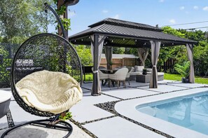 A poolside area with a covered seating area, a swing chair, and a stone-tiled deck. - Tulum Vibes House.
Perfect for relaxation and entertaining. (Jupiter)