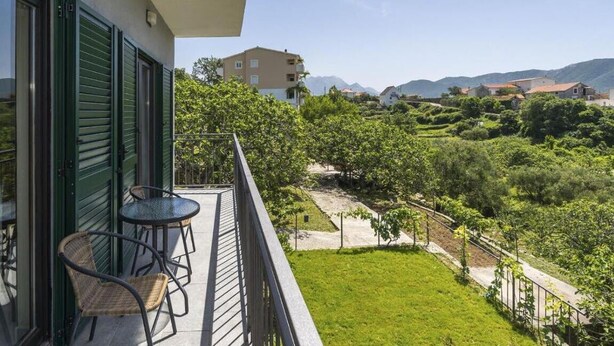 A balcony with a view of a lush green landscape and distant mountains.