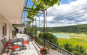 A balcony with a table and chairs, overlooking a river and green landscape. - Gorgeous home in Ricice with sauna (Ricice)