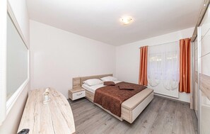 A bedroom with a bed, bedside table, and a window with curtains. - Gorgeous home in Ricice with sauna (Ricice)