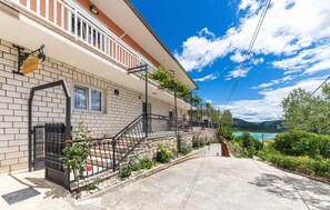 A two-story building with a balcony, a stone wall, and a view of a body of water. - Gorgeous home in Ricice with sauna (Ricice)