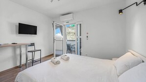 A hotel room with a bed, a desk with a chair, a TV mounted on the wall, and a balcony with outdoor seating. - Beach front apartment in Vodice with WiFi (Vodice)
