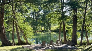 Un cadre paisible au bord d’un lac, avec un sentier en pierre menant à un espace de repos agrémenté de chaises en bois.