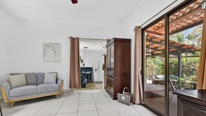 Een woonkamer met een bank, een eethoek en een glazen schuifdeur die leidt naar een terras.