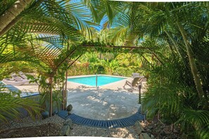A pool area with lounge chairs and a pergola. - Charming poolside Coco Cottage (Playa Hermosa)