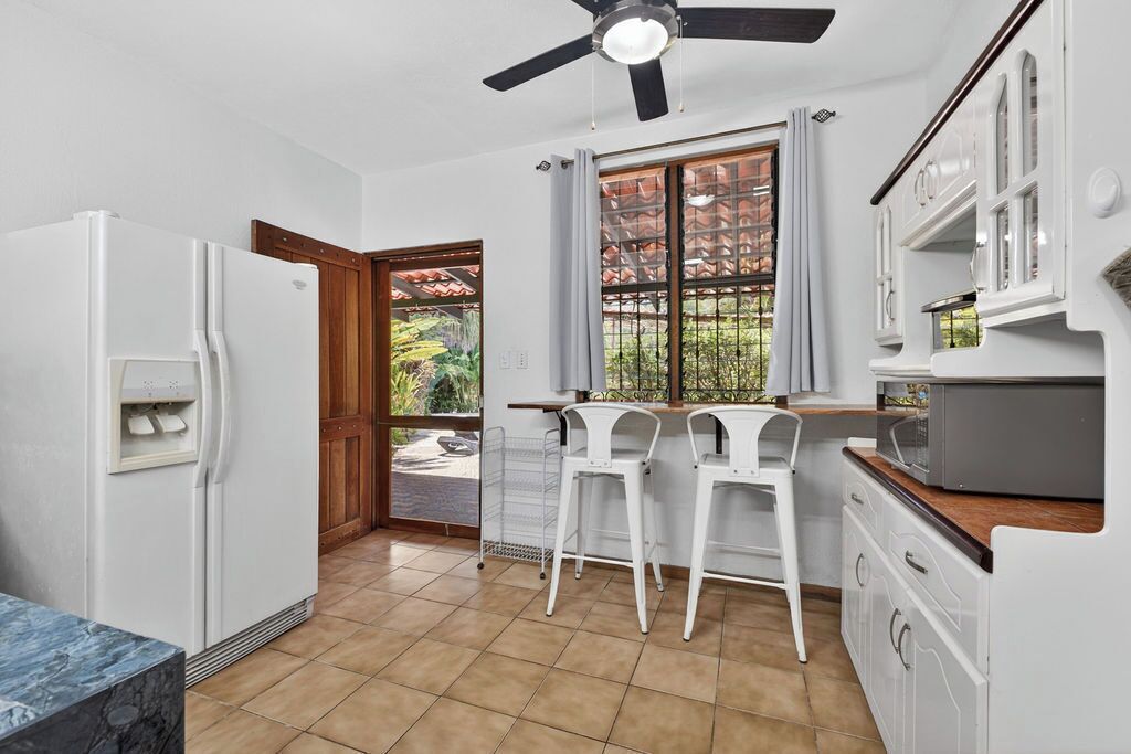 A kitchen with a refrigerator, microwave, and bar stools.