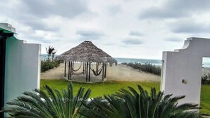 A thatched-roof structure in a grassy area with a view of the sea. - La Villa Playera. (Puerto Cayo)