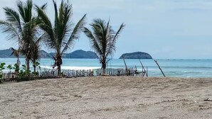 A beach with palm trees and a wooden fence.