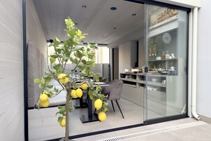 A modern dining area with a glass partition, a table with chairs, and a decorative lemon tree.