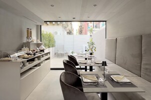 A modern dining area with a long table, chairs, and a buffet counter.