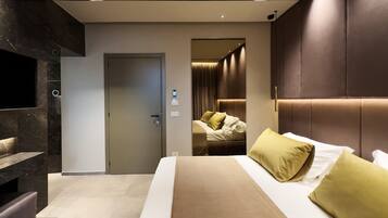 Una habitación de hotel moderna con una cama grande, una zona de estar y un espacio para dormir separado con vistas.