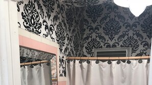 Un baño con lavamanos blanco, espejo y cortina de ducha.