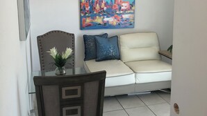 Una sala de estar con sofá, una mesa de comedor con sillas y un cuadro en la pared.