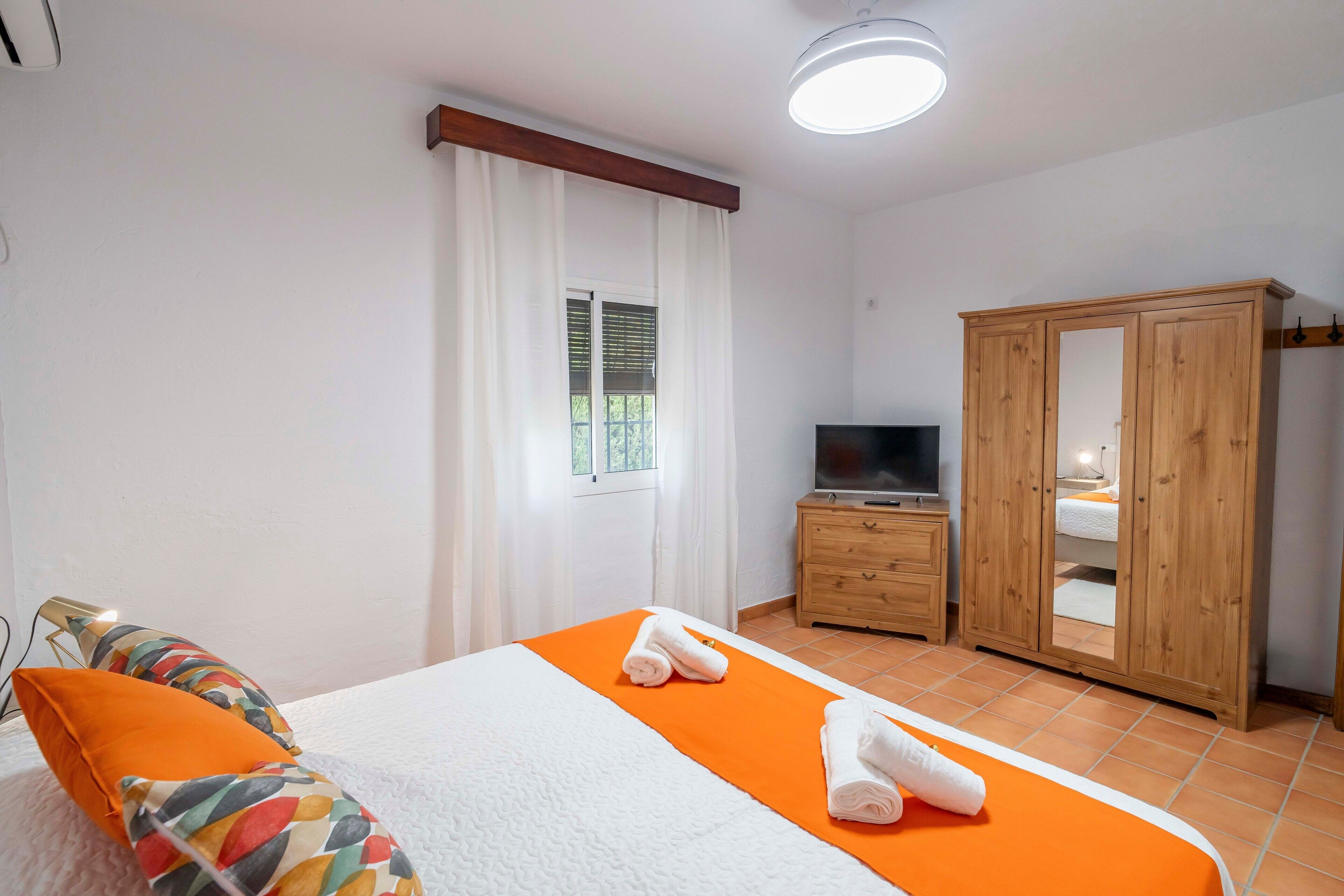 Ein Hotelzimmer mit einem Bett, einem Fernseher, einem Kleiderschrank und einem fenster mit Vorhängen.