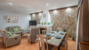 Un coin repas avec une table dressée pour quatre personnes, un canapé, un téléviseur et un mur décoratif.