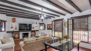 A living room with a sofa, a glass coffee table, a fireplace, and a television. - Rural House 'Carula' with Private Pool, Wi-Fi and Air Conditioning (La Puebla de Cazalla)