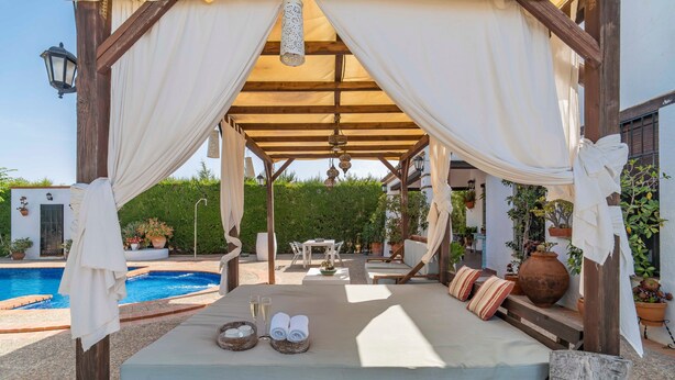 A covered outdoor seating area with a bed, a pool, and potted plants. - Rural House 'Carula' with Private Pool, Wi-Fi and Air Conditioning (La Puebla de Cazalla)