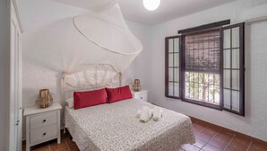 A bedroom with a bed, a nightstand, a window with blinds, and a ceiling light. - Rural House 'Carula' with Private Pool, Wi-Fi and Air Conditioning (La Puebla de Cazalla)