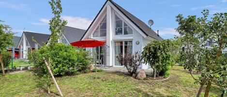 A modern house with a large front porch, a satellite dish, and a red umbrella.