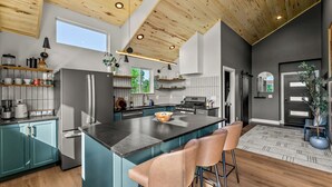 A modern kitchen with a large island, bar stools, and a view of the outdoors. - Golden Heights - Sauna + 180 Degree Views + Hot Tub (Cripple Creek)