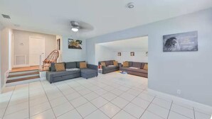 A spacious living room with a sofa set, a staircase, and a wall with a religious quote.