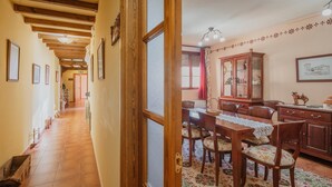 A hallway with wooden beams and a dining area with a wooden table and chairs.