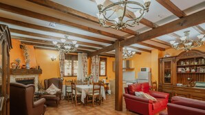 A dining area with a wooden ceiling, chandeliers, a fireplace, and a red sofa.