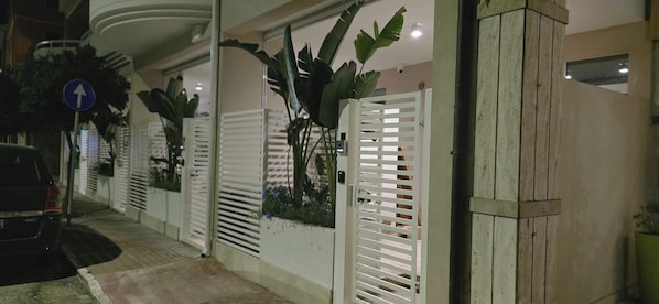 A gated entrance with a blue directional sign, a parked car, and a potted plant.