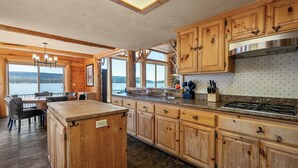 A spacious kitchen with wooden cabinets, a granite countertop, and a view of a lake. - Northern Exposure Lakefront (Fawnskin)