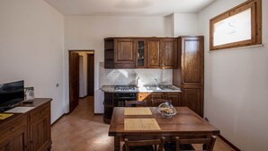A compact kitchen with wooden cabinets, a stove, and a dining table with chairs.