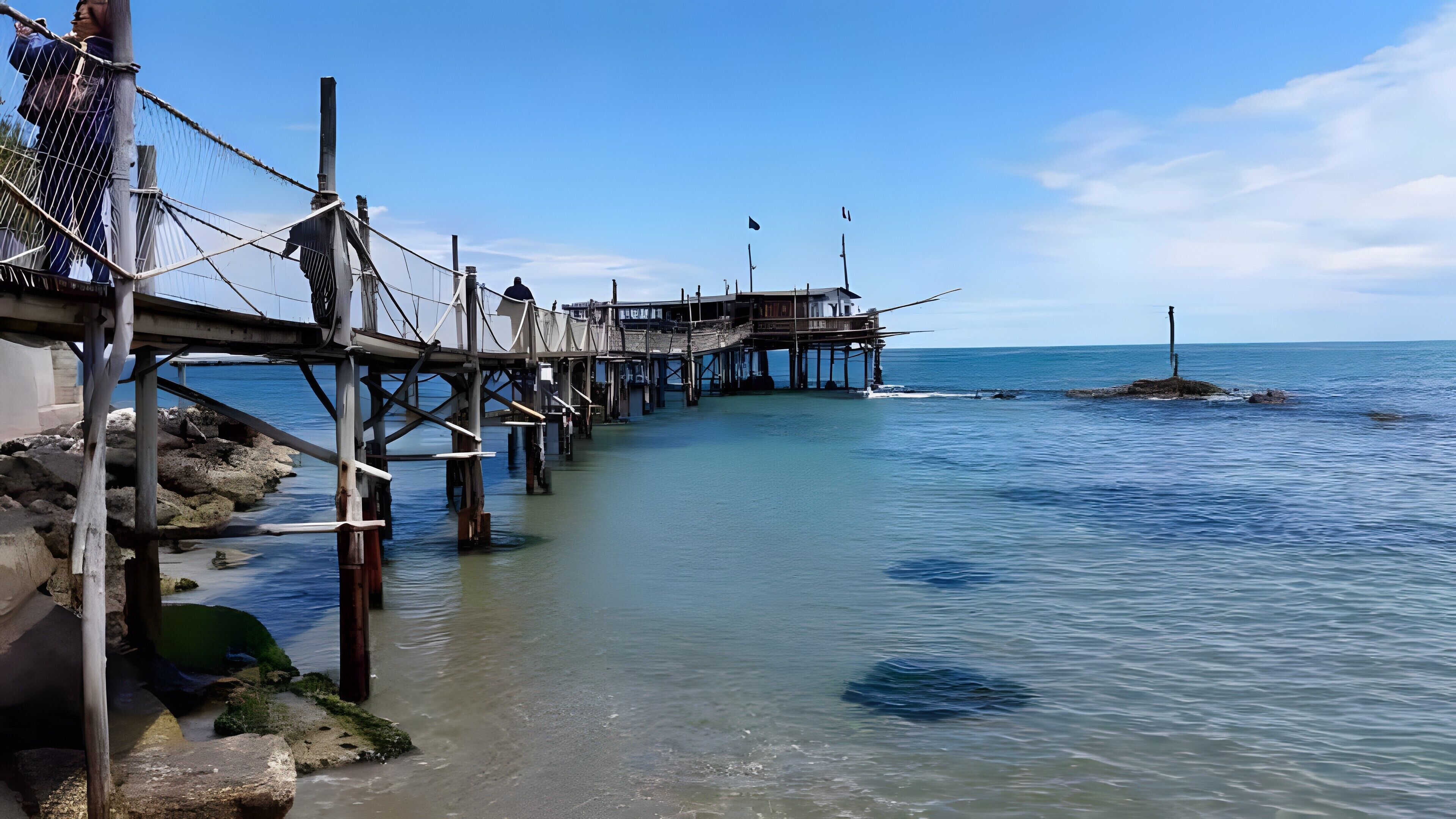 A pier extending into calm waters with a clear sky.