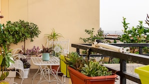 Un balcon agrémenté de plantes en pot, une table et des chaises en métal blanc.