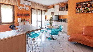 Un salon moderne comprenant un canapé, une table à manger avec des chaises, un coin cuisine et un téléviseur.