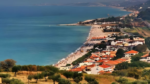 Une ville côtière dotée d’une plage, de bâtiments et offrant une vue dégagée sur la mer.