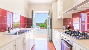 Cozinha moderna com armários brancos, pia de aço inoxidável e fogão a gás.