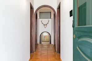 Un passadís amb terra de rajola, portes de fusta i un cap de cérvol penjat.