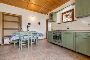 A kitchen with a dining table, chairs, a stove, and green cabinets.