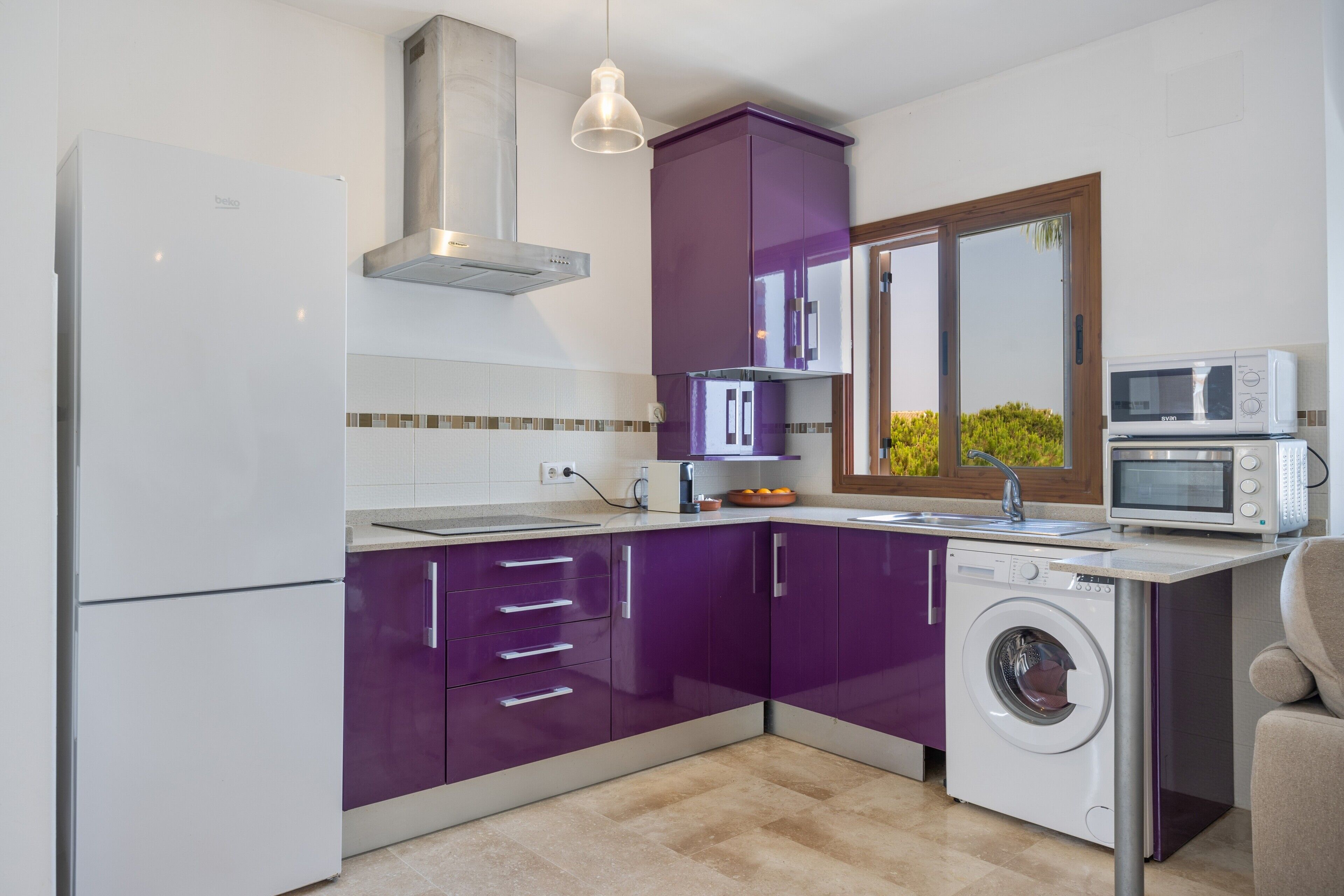 Een moderne keuken met een wasmachine, een magnetron en een inbouwoven.